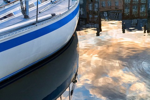 Detail of a yacht, houses of the old town reflected in the harbour basin, Honfleur in the evening,