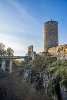 Mighty castle ruins on a hill in the evening sun, surrounded by landscape and trees, Wolfstein
