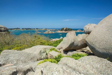 Beach with rocks and sand at the Plage Saint Guirec, with clear blue sky and colors as in the
