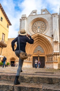 Tourist climbing the steps of tarragona cathedral in catalonia admiring the rose window on a sunny