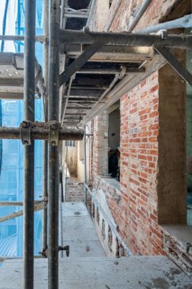 Scaffolding surrounds a building under renovation, showcasing exposed brickwork and construction