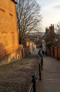 People walking on Steep Hill in evening light, Lincoln, Lincolnshire, England, UK