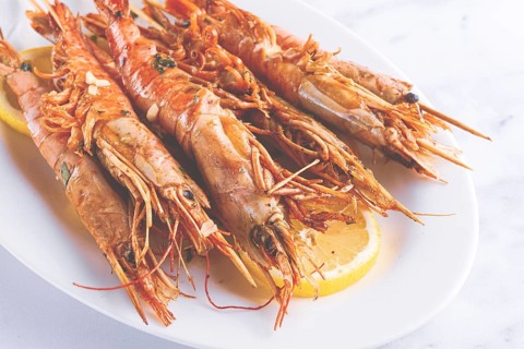 Freshly grilled prawns served, on a white platter, with lemon slices, for a delicious seafood
