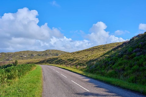 Lonely road snakes through green hills under a clear sky, Gruinard Beach, First Coast, Little