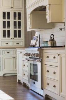 White painted maple wood antique style cabinets with tan coloured quartz countertops in kitchen