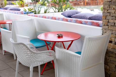 Brightly colored outdoor seating features white chairs and a red table, creating a cheerful