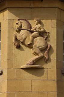 Stone portrait, boy on horse, stone relief on building, rearing horse with rider, sculpture,