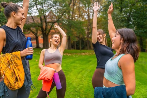 Group of enthusiastic young women friends raising their arms in celebration after a successful