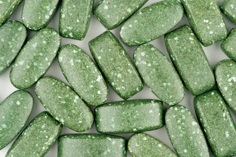 Close-up of green pills scattered on white background