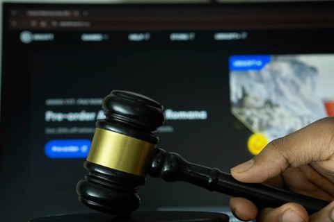 Dhaka, Bangladesh- 20 June 2025: A hand holds a gavel in front of a computer screen displaying