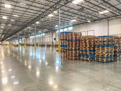 Massive Empty Industrial Warehouse Interior With Stacked Pallets