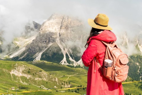 Close up asian female hiker with backpack and straw hat looking at misty mountain peaks deep valley