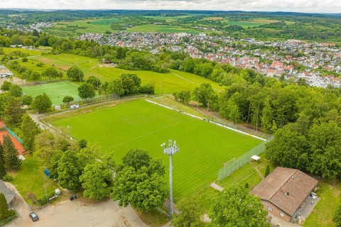 Green sports fields in a rural area with surrounding fields and a village, Sportplatz Aidlingen,