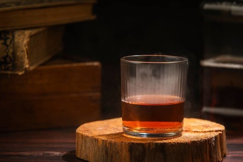 Glass of whiskey with light steam on wood in a cozy setting