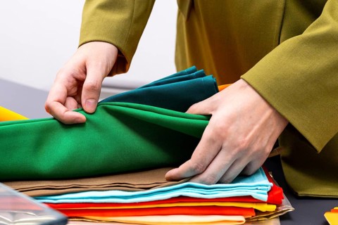 An image consultant arranges a variety of colorful fabrics during a consulting session. The