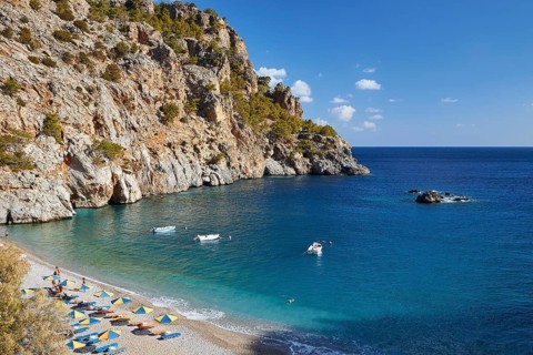Lonely rocky bay with crystal clear water and a few boats on the shining sea, Ahata Beach, Ahata,
