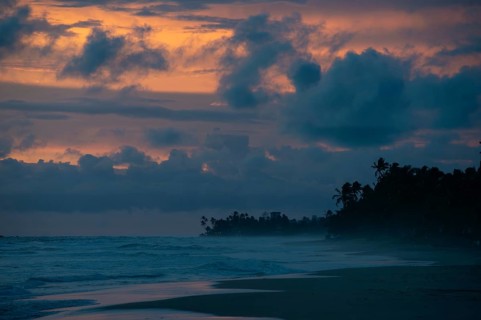 Captivating view of a sunset over a misty beach in Sri Lanka. The sky displays dramatic hues of