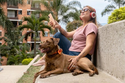 Middle-aged woman enjoying outdoors and listening to music, accompanied by her pet in the tropical