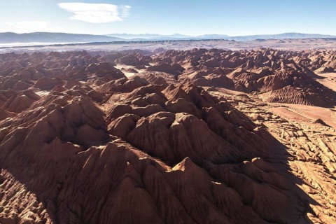 Aerial view of the rugged terrain of Devil's Desert in Salta, Argentina, showcasing its unique red