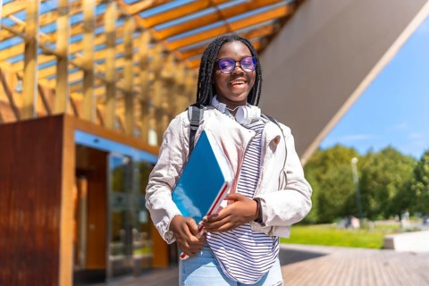 Proud african female student walking outside the university in a sunny day of spring