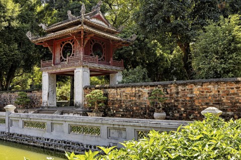 A red pavilion stands next to a moat, surrounded by trees and a brick wall, The Temple of