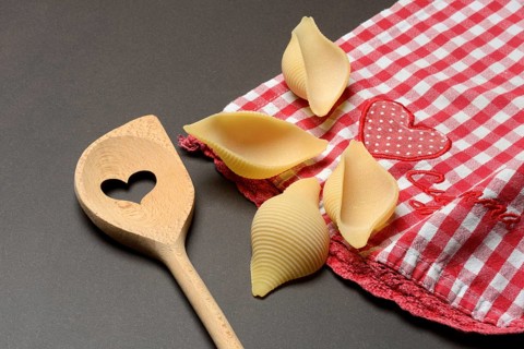 Conchiglione with wooden spoon, Italian pasta variety against a dark background, Italy