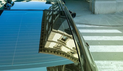 Reflection of a residential building in the rear window of a parked car, Florence, Italy