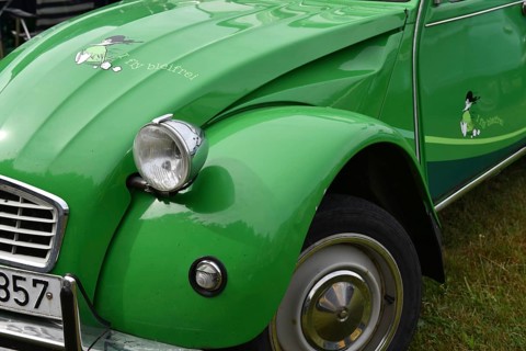 Close-up of a green Citroën 2CV with a cloverleaf motif, showing the front end, vintage Citroën