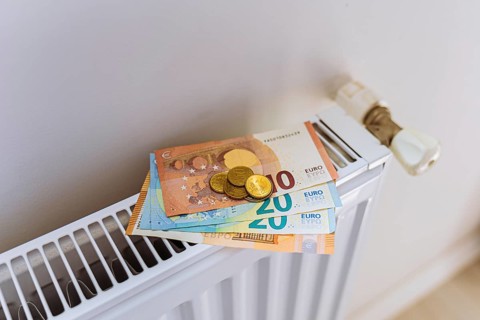 Euro banknotes and coins on radiator during winter heating season. Concept of rising household