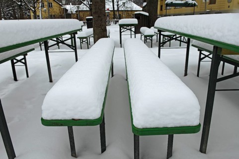 Winter in the English Garden, snow-covered beer garden tables and benches, Munich, Bavaria, Germany