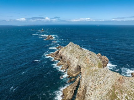 Aerial view of Pointe du Raz with the Phare de la Vieille lighthouse in front of a rocky island,