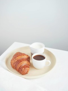 Simple continental breakfast on the table croissant, coffee cup and milk jug