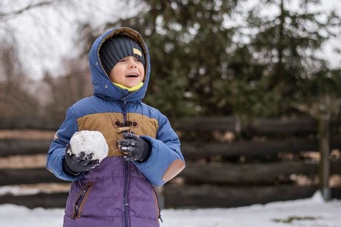 Six year old boy smiling with runny nose and snowball