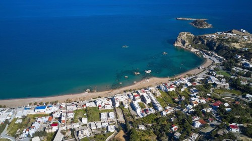 Aerial view of a coastal town with white houses and a calm blue sea in the background, Stegna