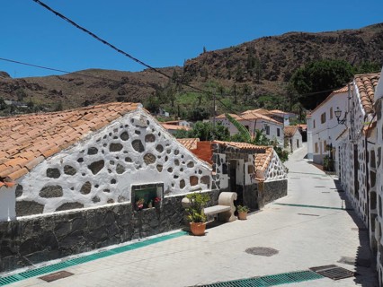 Stone houses along a village road in Fataga in a mountainous landscape under blue sky, Barranco de
