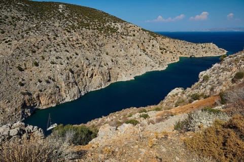 A secluded rocky bay with deep blue water and a hidden boat, Rina, harbour, Vathi, Vathys,
