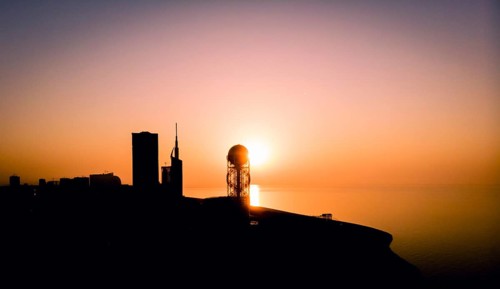 Panoramic silhouette of Batumi city skyscrapers from distance with blue sea water in the background