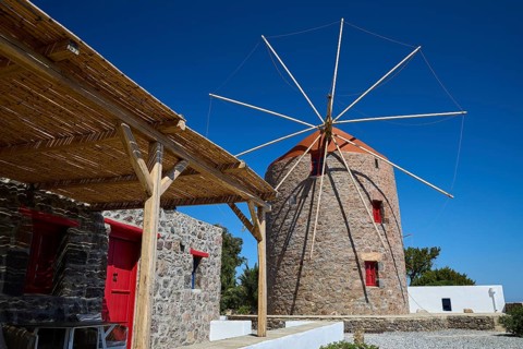 Stone windmill with red roof and wooden canopy under clear sky, Trypiti, Tripiti, village, Milos,
