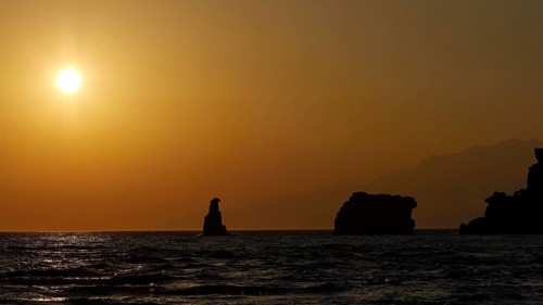 Sunset at sea with silhouette-like rocks under a warm orange sky, sunset, South of the Amari Basin,
