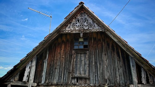 Close-up of an old wooden gable of a traditional wooden house with antenna under blue sky, Croatia