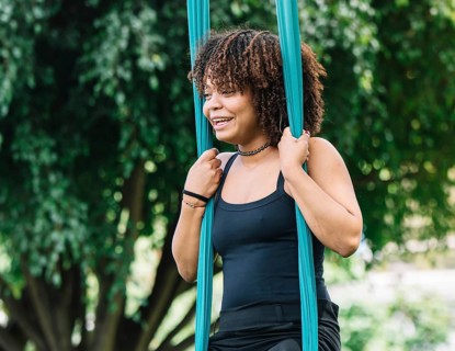 A black woman performs aerial acrobatics on silk in a scenic Bogota park She displays strength and