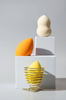 A visually appealing display of cosmetic sponges, including vibrant orange and yellow, arranged on