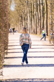 Woman walking along a tree-lined path. Spring mood and relaxed atmosphere in sunny weather,