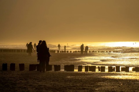 Winter on the North Sea, sunset at sea, beach walkers, coastal protection, through wooden posts,