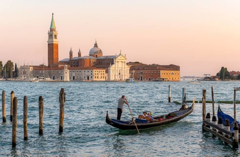 Gondolier with Venetian gondola on the lagoon, in the back island of Isola di San Giorgio Maggiore