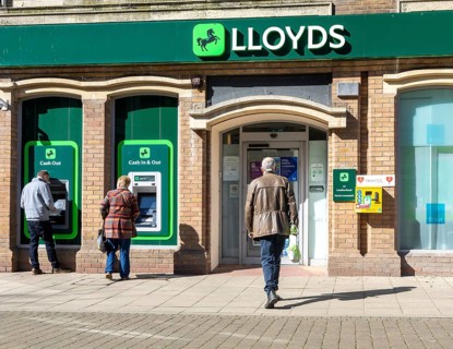 People using ATM cash machine at branch of Lloyds Bank, Lowestoft town centre, Suffolk, England, UK