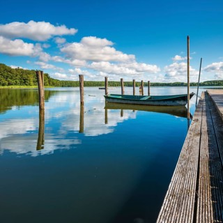 Jetty with rowing boats at Moderfitzsee under blue sky with cumulus clouds in summer, Himmelpfort,