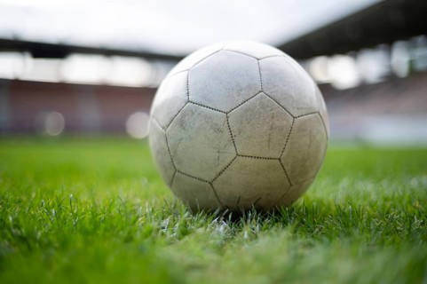 White soccer ball lying on the grass at stadium in Lubin, Poland
