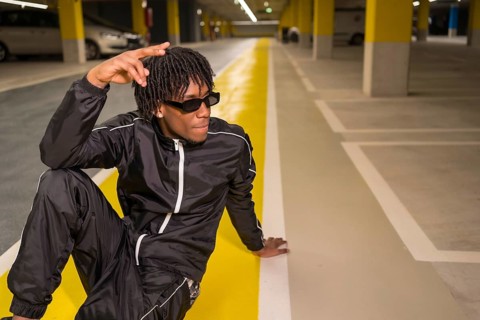 African american Hip hop artist sitting posing on a garage