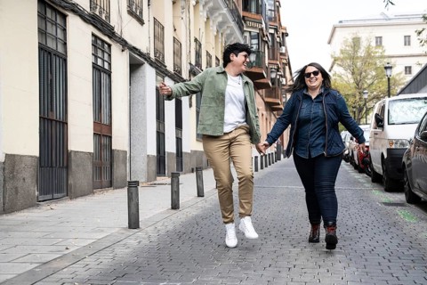 A happy lesbian curvy couple strolls hand in hand down an urban street, sharing a moment of joy and